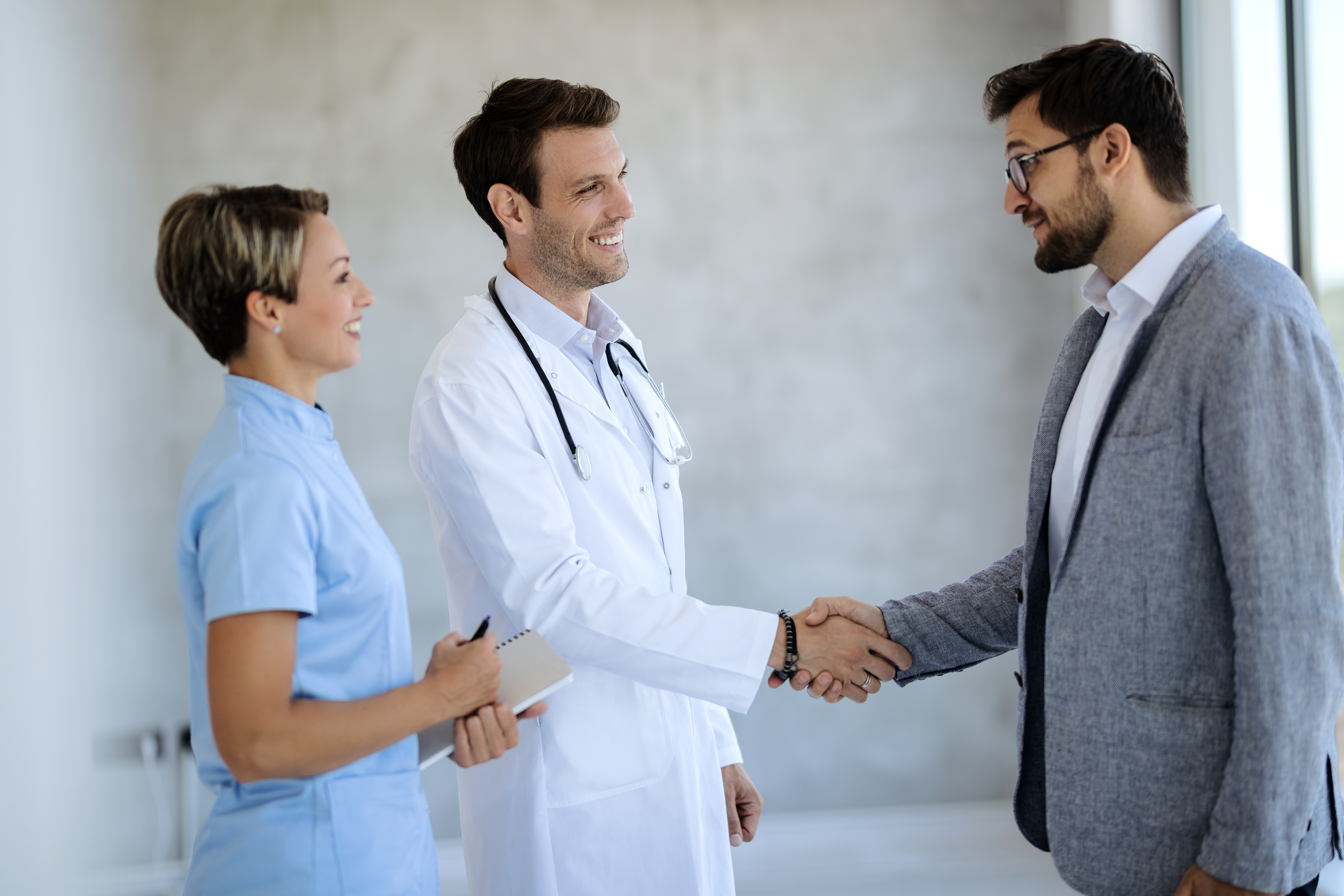 Happy doctor shaking hands with a businessman at medical clinic.